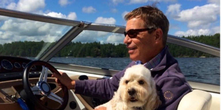 Randall Oliphant conduit un bateau avec un chien sur ses genoux.