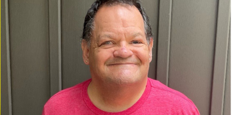 Photo de Shawn tout sourire, portant un tee-shirt rouge du camp Lake Joe d’INCA.