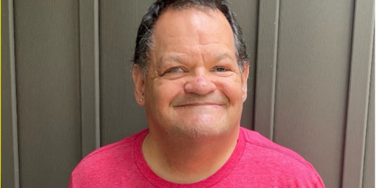 Photo de Shawn tout sourire, portant un tee-shirt rouge du camp Lake Joe d’INCA. 