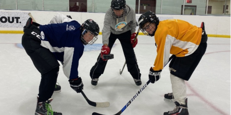 A puck drop. Hockey players, Brayden, Mathew and Eli during practice on the rink.