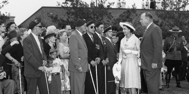 Sa Majesté la reine Elizabeth II rencontre Ralph Misener, alors président d’INCA, ainsi que des anciens combattants ayant une limitation visuelle dans le jardin odorant d’INCA (Toronto, 1959).]