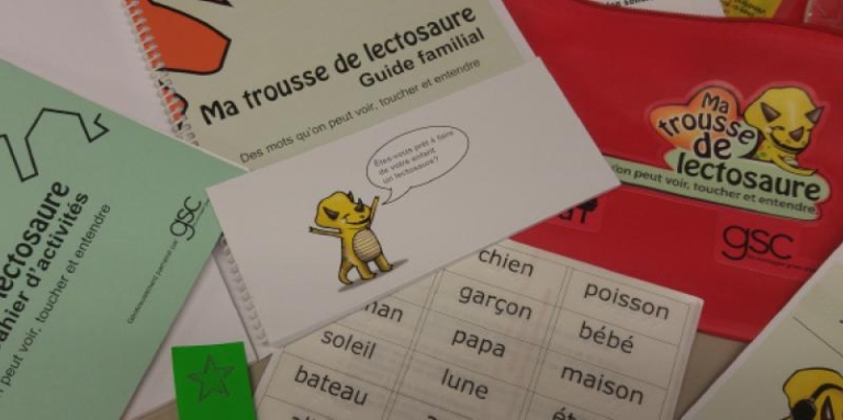 Aperçu du contenu de la trousse: un cahier d'activité, un guide familial, des étiquettes de mots, une petite mallette en tissus rouge et plus encore.