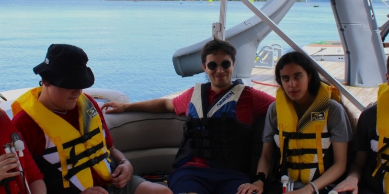 5 jeunes adultes portant une veste de sauvetage sur un bateau.