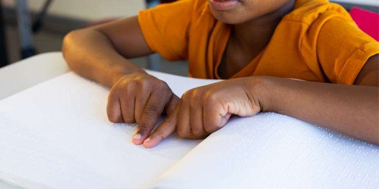 Un jeune enfant lit un livre en braille.