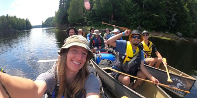 Un groupe enthousiaste de participants au camp Lake Joe d’INCA pagaie sur un lac calme entouré d'une forêt luxuriante dans le parc Algonquin. 