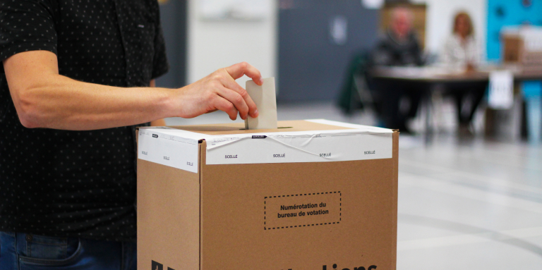 Un homme dépose son bulletin de vote dans une boîte d'Élections Québec