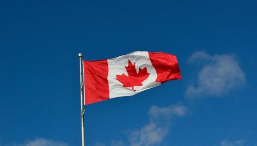 Un drapeau canadien flotte dans un ciel bleu et clair.