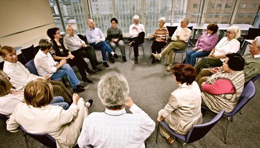 Un grand groupe de 17 personnes se réunit dans un groupe de soutien. Ils sont assis en cercle.