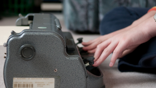 Hands typing on a Perkins brailler.