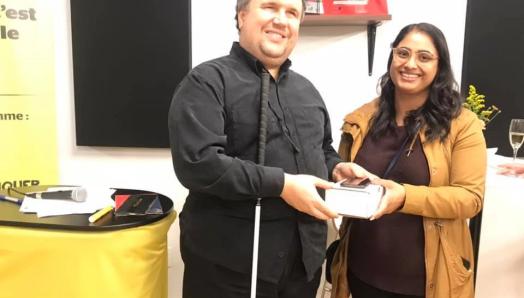 Aakruti Patel of West Groupe presents an iPhone to Sébastien Bolduc at the CNIB Montreal Hub.