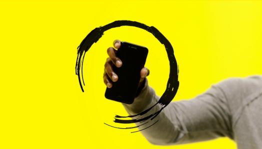 A hand holds a smartphone up in the air. The phone is surrounded by an illustration of a circular black swirl.