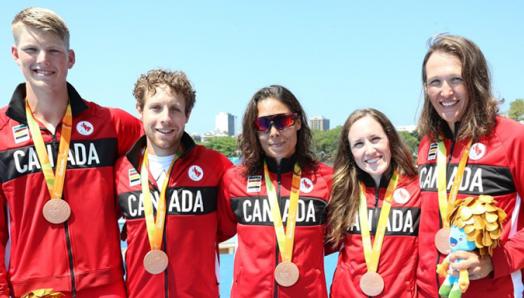 Victoria, en compagnie de deux hommes et de deux femmes, portant une veste de l'Équipe Canada et une médaille de bronze.
