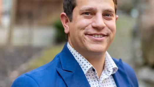 Jacob Charendoff smiles for a professional headshot. He is wearing a stylish blue suit.