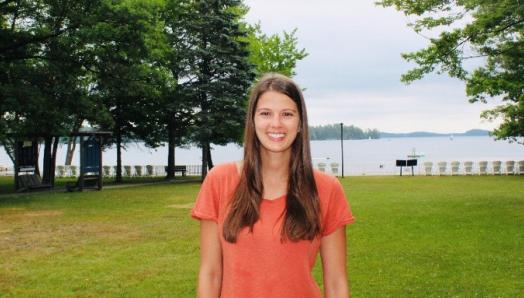 Ally standing on the grounds at Lake Joe, smiling with the water behind her.