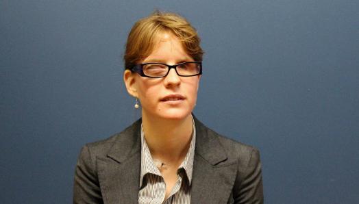 Elizabeth standing against a dark background wearing professional clothing and smiling for the camera.