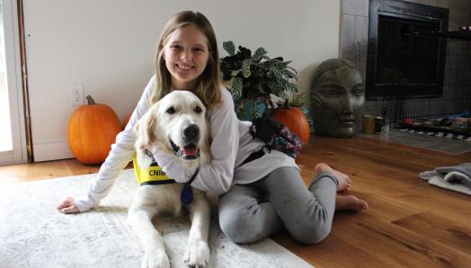 Dani and George sitting on her living room floor; Dani has her arm around George and both are smiling for the camera