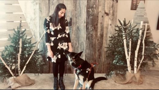 Stela Trudeau et son chien-guide berger allemand échangeant un regard, devant un fond de photo sur le thème de Noël.