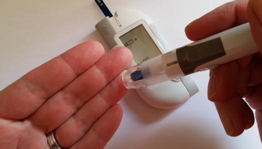 A woman checks her blood glucose level by poking her finger and using a blood glucose meter.