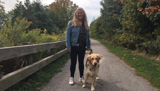 oto of Lindsay and Charlie walking along a pathway in a park on a sunny day, smiling for the camera.