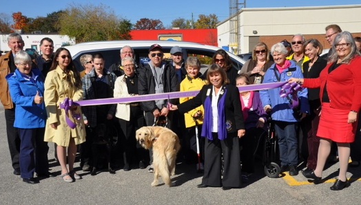 In 2015, Barb Ennis poses at a ribbon-cutting ceremony when she, as Lions District Governor for A12, purchased a brand new van to enhance client service. This van is now in service at CNIB Lake Joe!