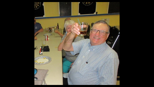Wayne Laffin, assis à une table avec d'autres invités lors de la soirée de la Légion à MacTier, lève son verre avec un grand sourire.