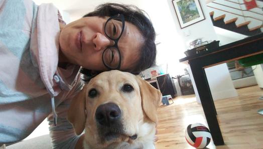 Yuko Imai sitting on the floor taking a selfie with Rhonda, a yellow Labrador-Golden Retriever cross.