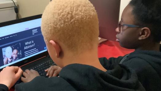 Une photo par-dessus l'épaule de Munashe et Munopahse assis devant leur ordinateur portable et travaillant sur leur projet de collecte de fonds.