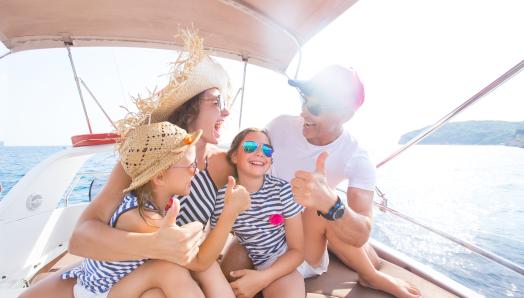 A family of four give the 'thumbs up' while cruising on their boat.