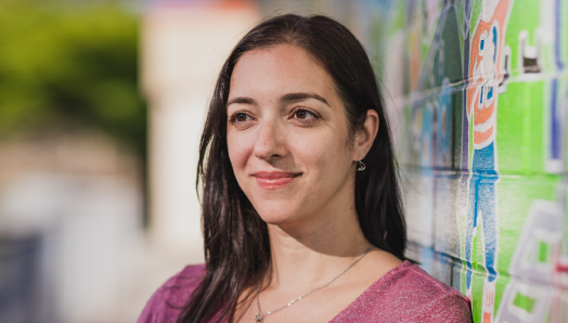 Une photo-portrait de Stefanie Volpe à côté d'un mur rempli de graffitis colorés.
