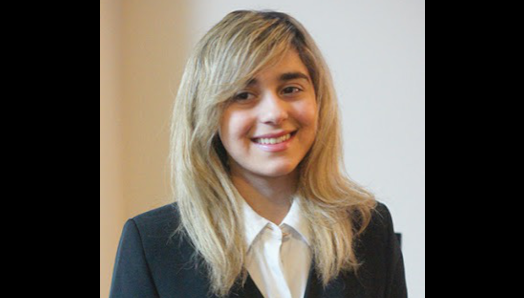 Avesta pose pour une photo d'identité professionnelle. Elle porte un blazer noir et un chemisier blanc.