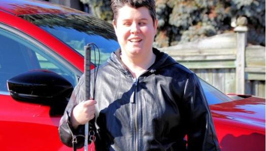 Jade Stolar standing outside holding a white cane.