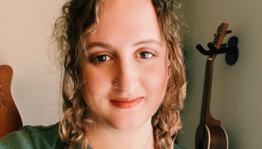 Taylor Gaudot is smiling for a photo wearing her hair in braids and a green top.