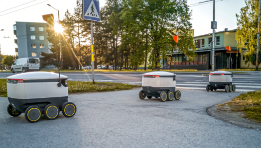 Trois automates de distribution de produits circulent sur le trottoir d'une ville.