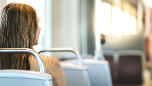 The Back view of a young woman riding the bus and sitting in a chair.