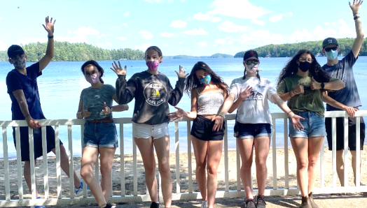 Seven 2021 seasonal staff members waving from the fencing on the waterfront.