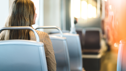 The Back view of a young woman riding the bus and sitting in a chair.