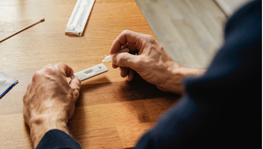 An elderly person using a COVID-19 at home rapid antigen test.