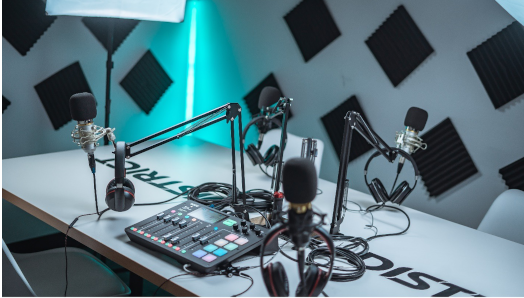 A desk with podcast equipment on top (microphones, headphones, cables, mixer)