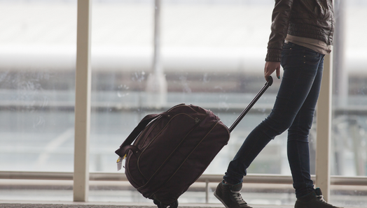 A young woman pulls their luggage in the airport terminal.