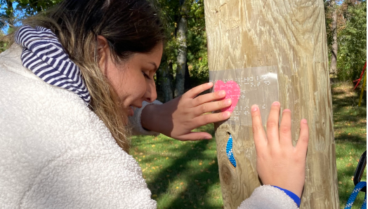 Un indice de chasse au trésor est affiché sur le mur d'escalade du lac Joe d'INCA. L'indice est écrit en braille et un jeune participant lit l'indice en braille avec ses mains.