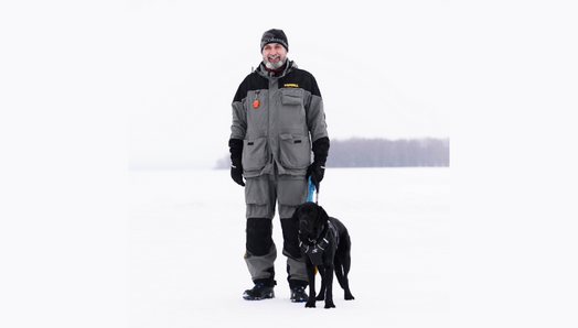 Lawrence and his guide dog enjoying the wintery great outdoors. They stand together on a snow-covered frozen lake.