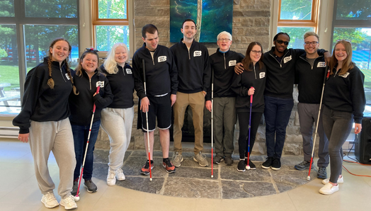 Some members of the CNIB National Youth Council at CNIB Lake Joe. The group poses for a photo in the lounge, standing in front of a window. From Left to right: Taylor, Alicia, Oceanne, Rilind, Caleb, Caelin, Abby, Eitel, Will and Emilee.