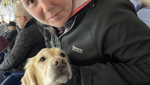 Kelly et son chien-guide, Maple, sont assis dans les stands de l’aréna Mary Brown’s Centre.