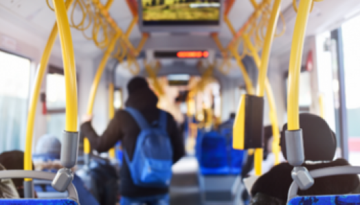 Interior of a city bus. Commuters sit and stand inside the bus.