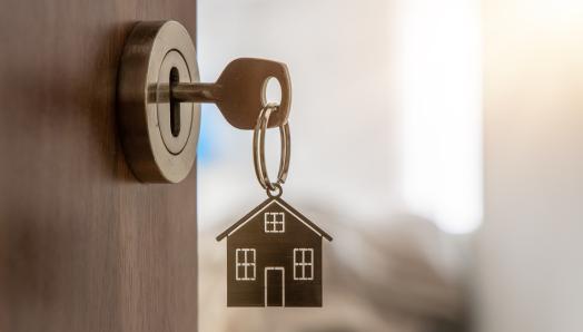 Une porte ouverte qui mène à un nouvel appartement. Un trousseau de clés pend dans la serrure de la porte.