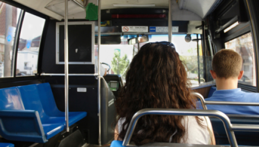 Intérieur d'un autobus urbain. Deux usagers voyagent assis dans l’autobus.
