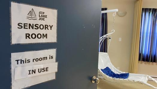 La porte de la salle multisensorielle du Centre Lake Joe d’INCA. Un panneau indique « Cette salle est en cours d’utilisation ». Il y a une chaise suspendue à l’intérieur de la pièce.