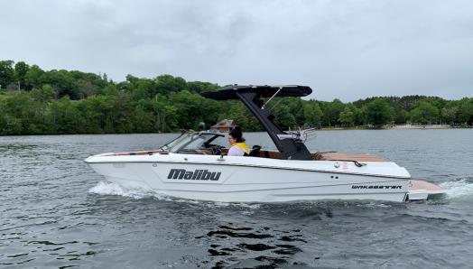 Bateau de ski nautique blanc sur le lac avec les mots « Malibu » et « Wakesetter » sur le côté.