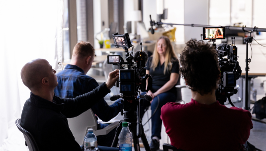 Diane Bergeron is interviewed by a film crew at CNIB Ottawa. The crew of three holds cameras and boom microphones. 