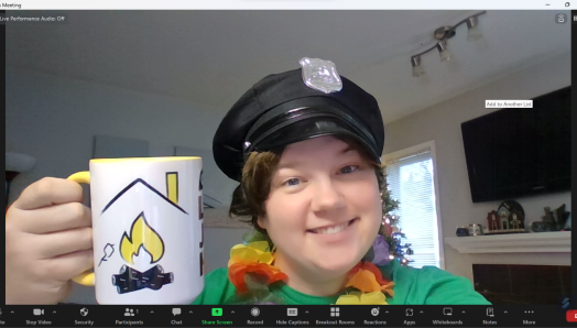 Sam est toute souriante sur l'écran Zoom. Elle porte un képi noir de policier, un lei hawaïen multicolore et tient une tasse à café de la marque LakeJoeINCA@LaMaison.